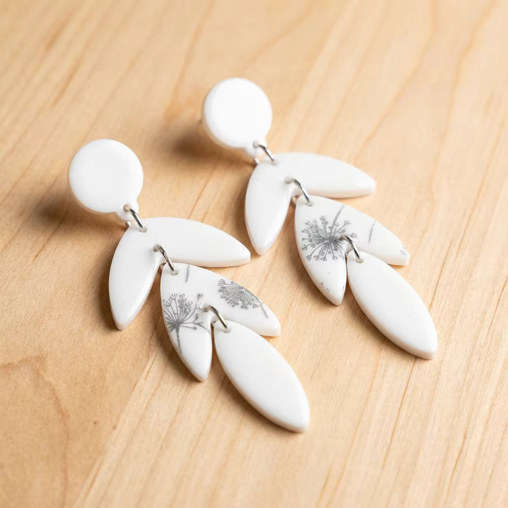White dangling earrings with leaves and dandelion motif