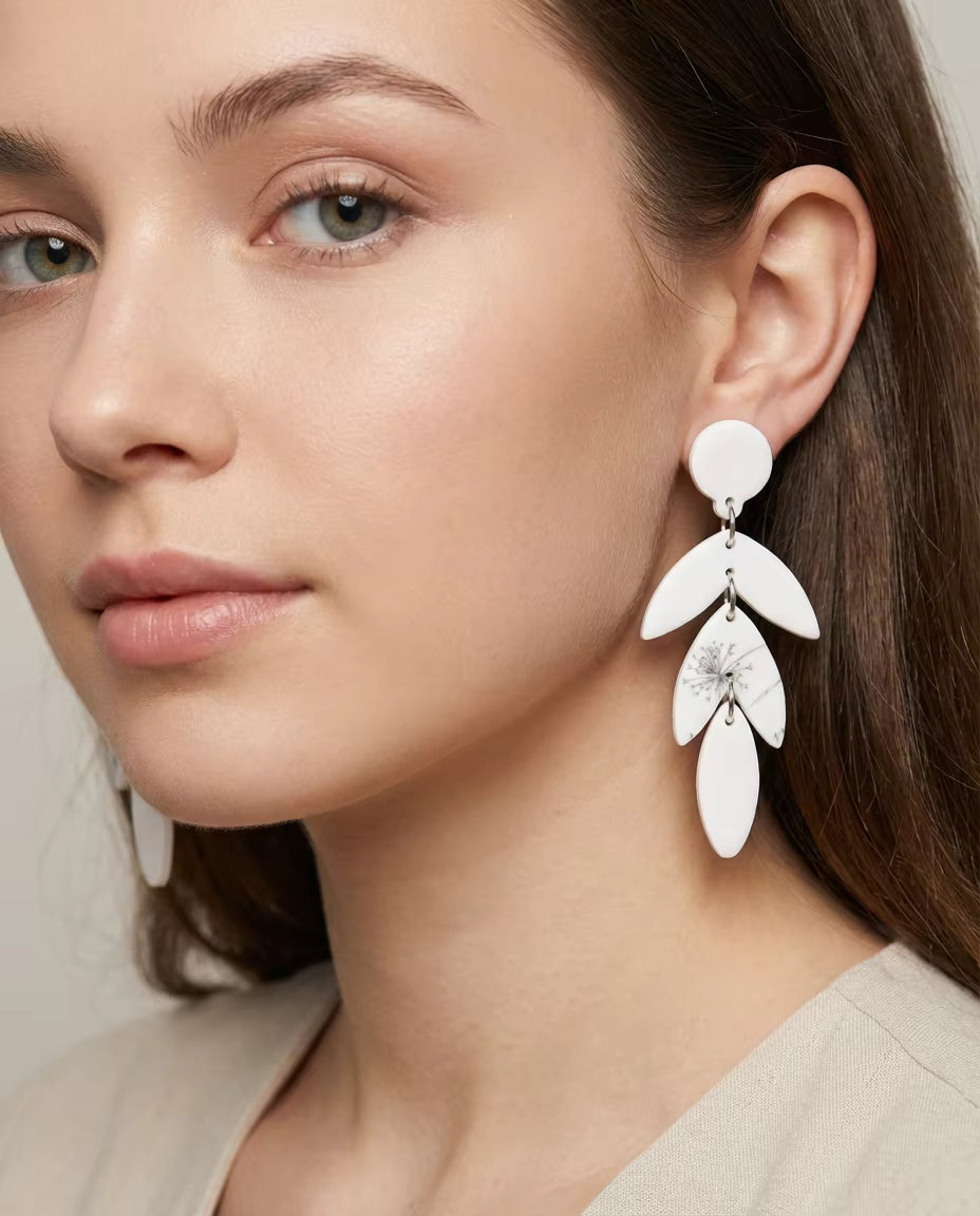 White dangling earrings with leaves and dandelion motif