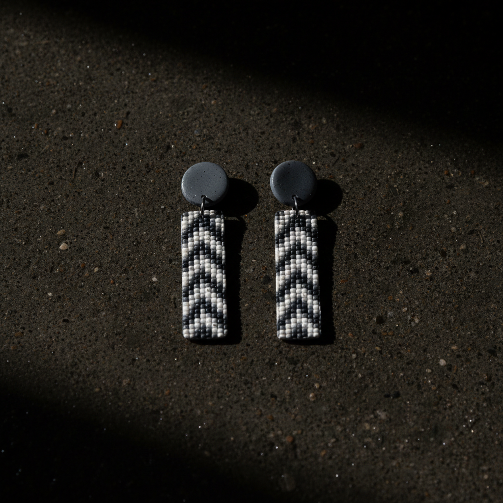 Dvodjelne chevron mozaik naušnice na mokrom betonu — editorial produkt foto